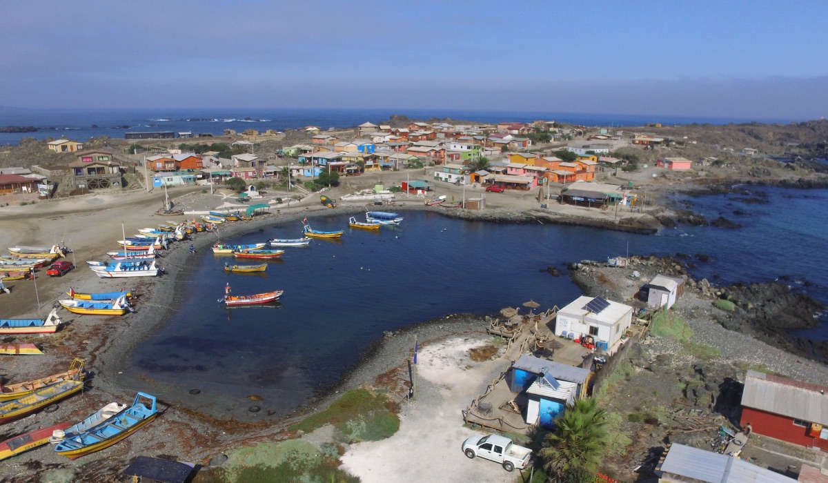 La caleta de Chañaral de Aceituno vista desde el aire, con los botes en la poza y las casas del pueblo detrás.