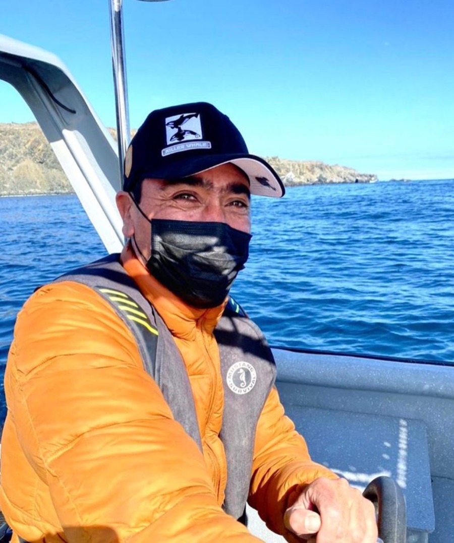El capitán de Turismos Orca al timón, con chaqueta naranja y el mar de la reserva detrás.